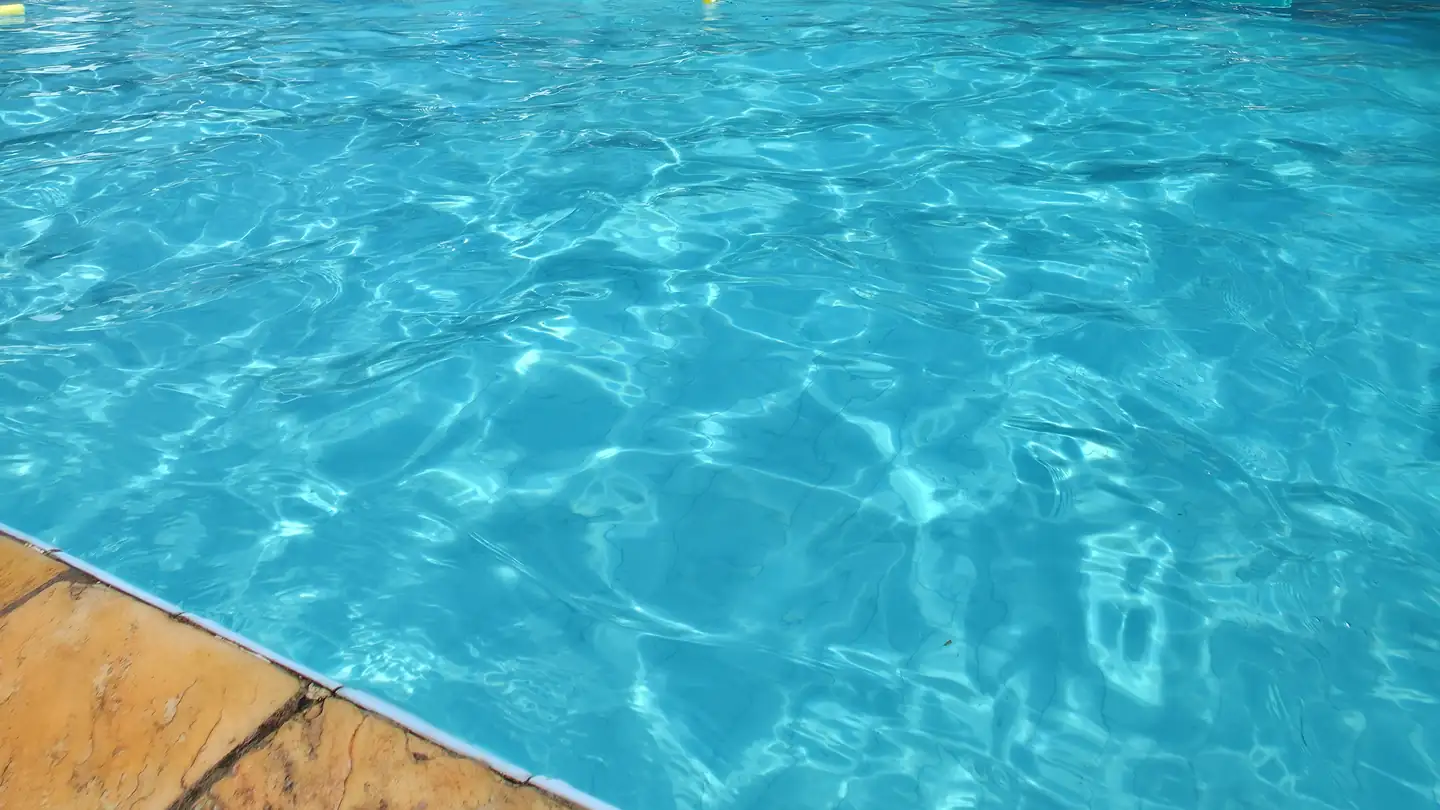 Lâmina de água turquesa da piscina da Chácara Santana em dia de sol