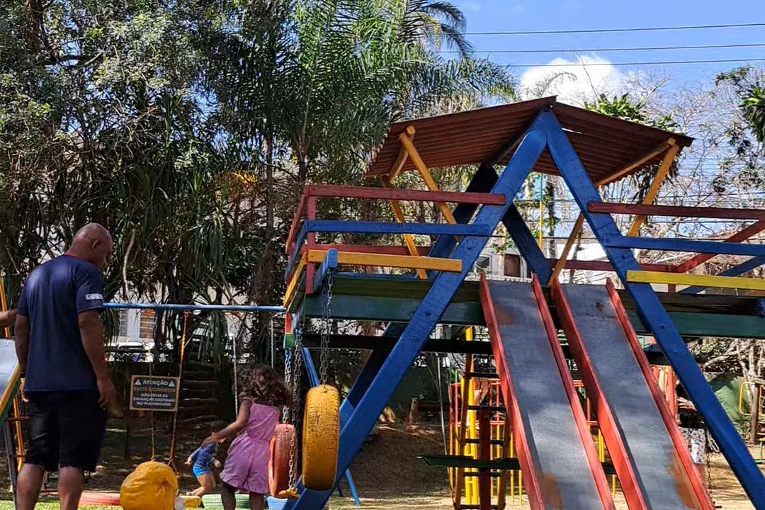 Playground com escorregadores coloridos e crianças brincando no gramado
