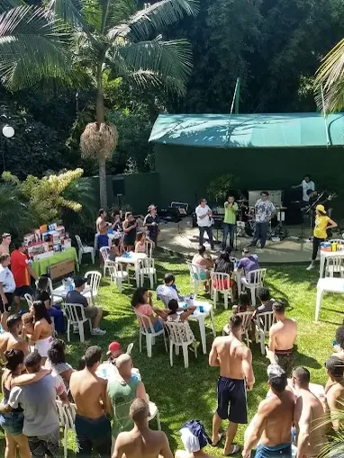 Área gramada com plateia em cadeiras diante do palco, vista de cima