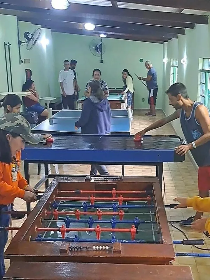 Salão de jogos com mesa de pebolim e mesa de ping-pong em uso