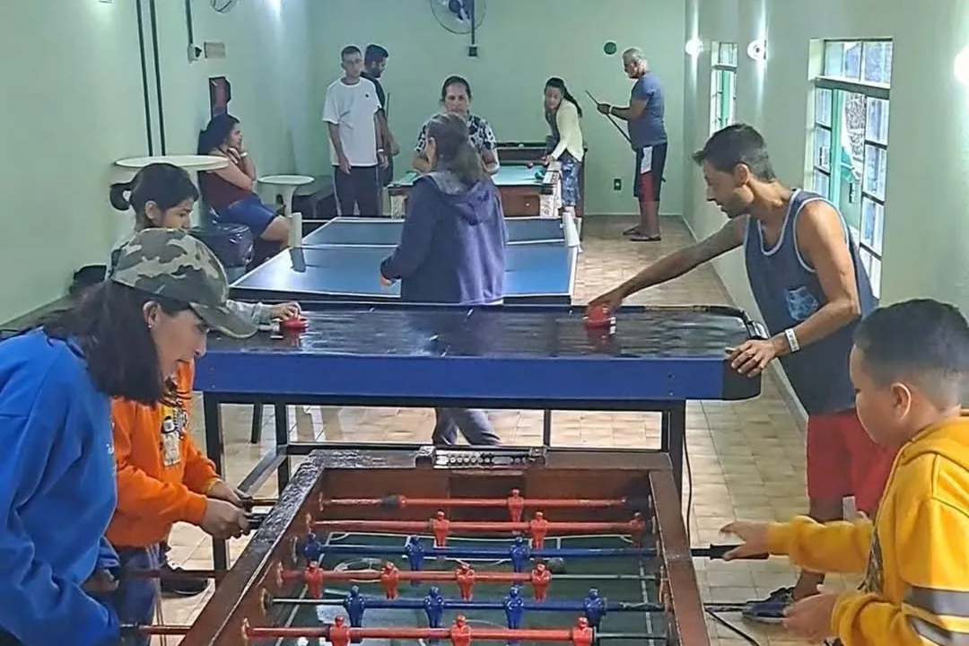 Salão de jogos com mesa de pebolim e mesa de ping-pong em uso